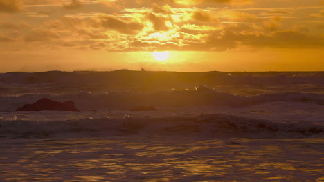 las olas del mar chocando en la playa al atardecer durante un día ventoso