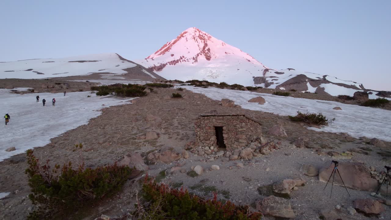 fotografía de un pequeño refugio de montaña con la montaña en el fondo - puesta de sol