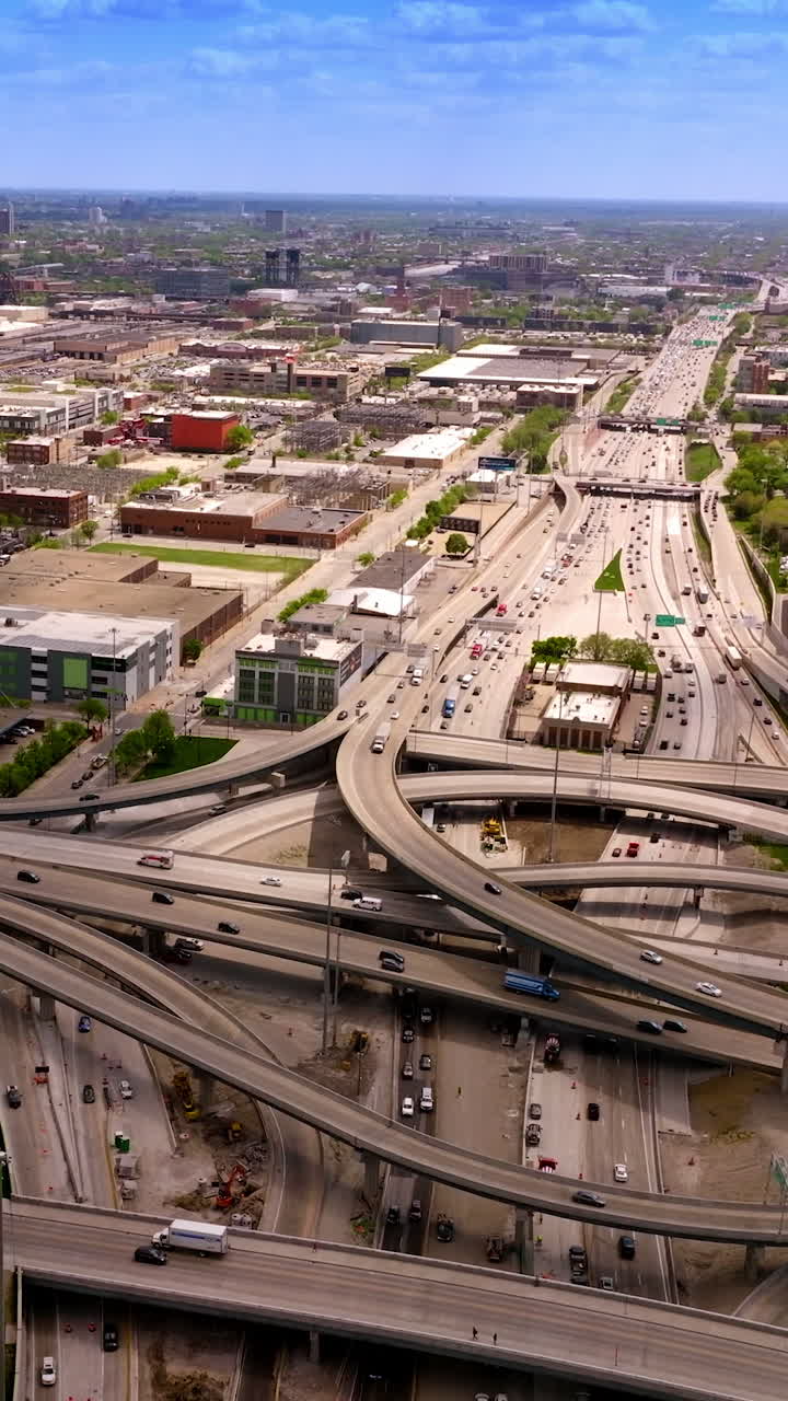 Road loops and junctions with multiple automobiles moving along. Low architecture of Chicago city. Aerial view. Vertical video