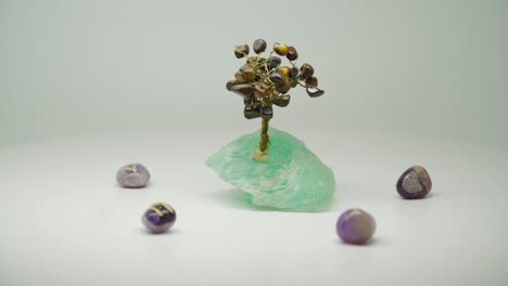 expensive crystal wire trees with green amethyst surrounded by five purple crystal on turntable - close up shot