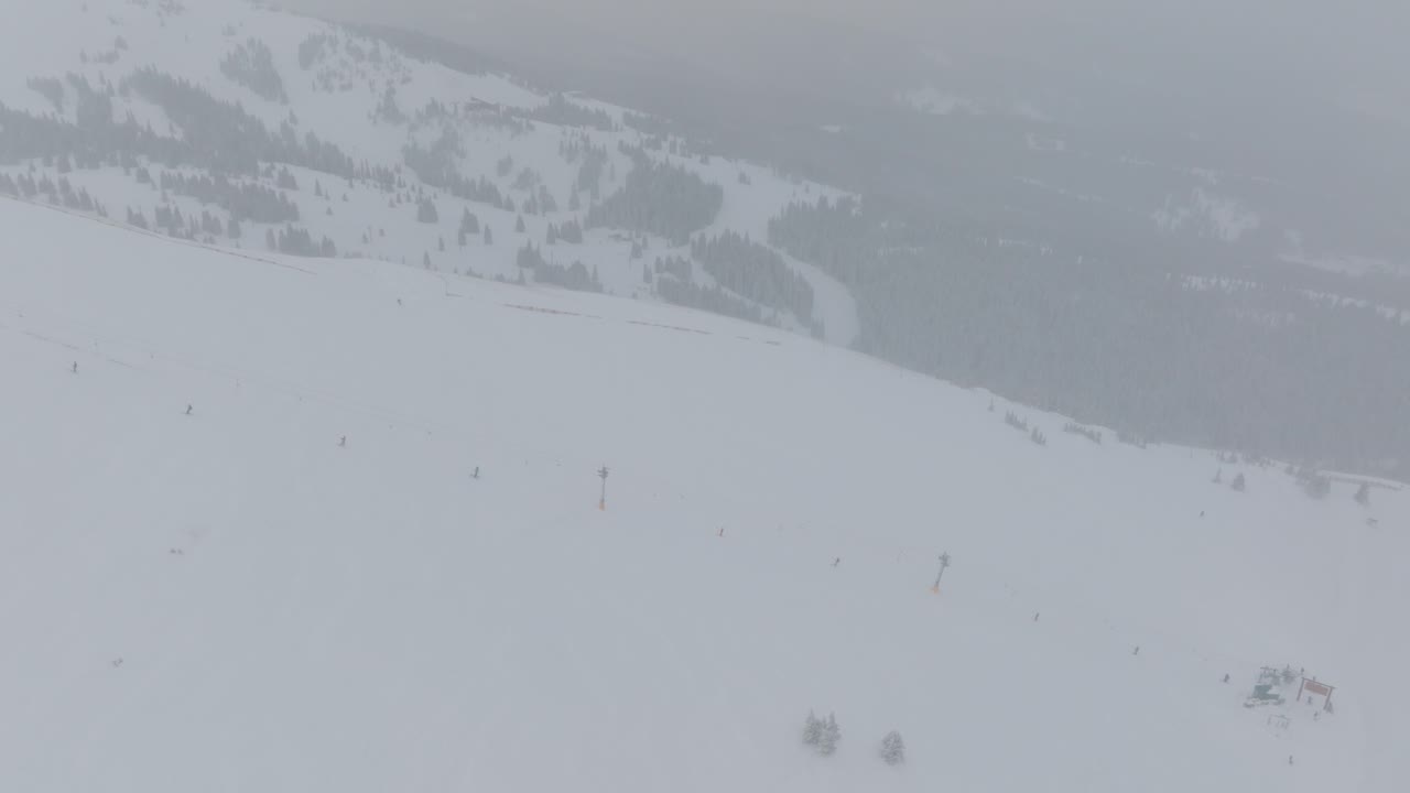 Aerial top shot of snow boarders snowboarding on Copper Mountain on a foggy morning in Colorado, USA.