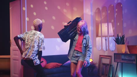 african american man and caucasian woman holding boom box dancing in a retro party at home