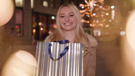 happy woman holding a gift bag at night