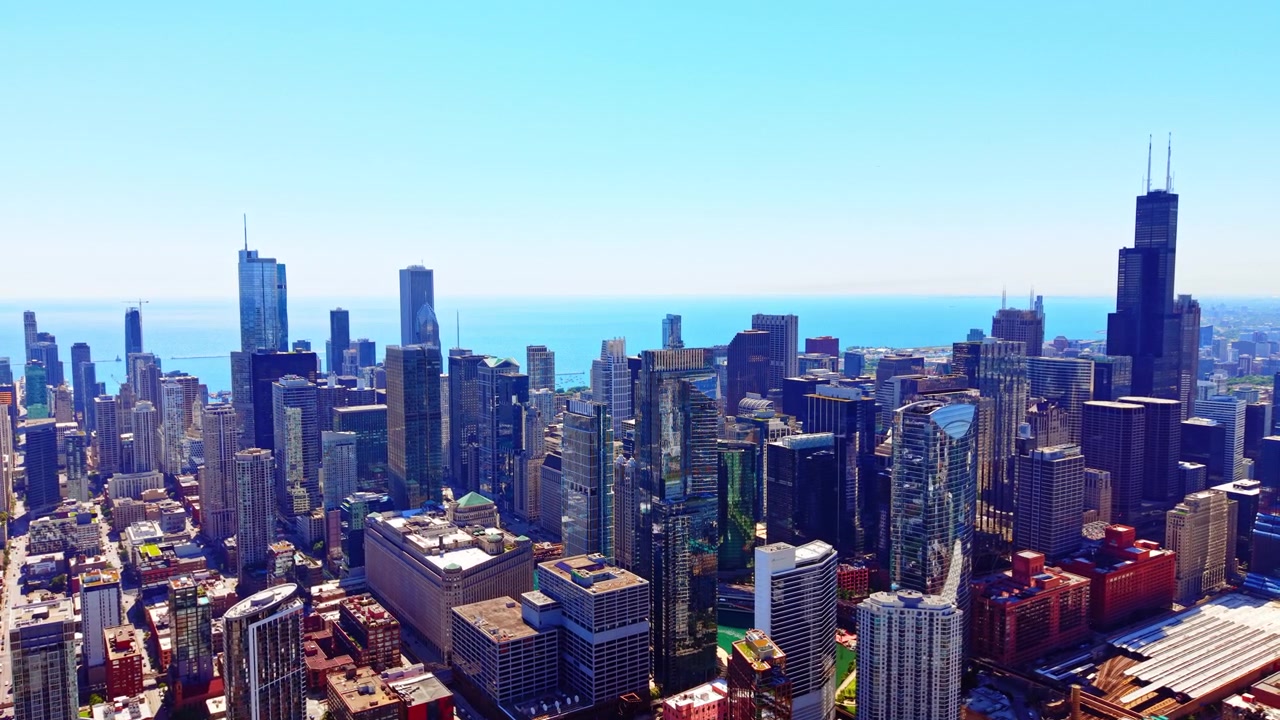 Skyline del centro di Chicago che si affaccia sul Lago Michigan, Illinois. Prospettiva aerea diurna di torri di vetro, acqua blu e costa distante sotto un cielo velato