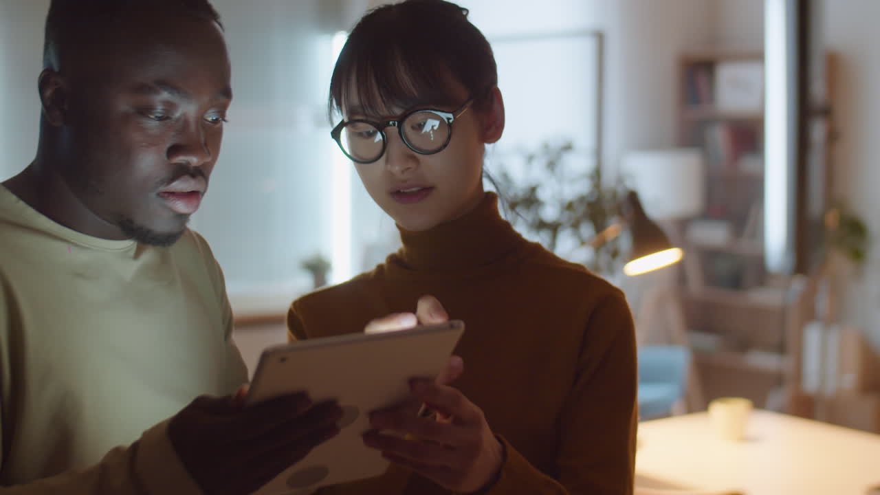 Multiethnic Colleagues Working on Digital Tablet in Office at Night