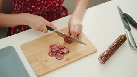 woman cutting sausage on a wooden cutting board