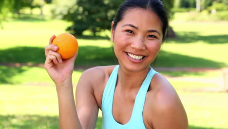 fit asian girl showing an orange