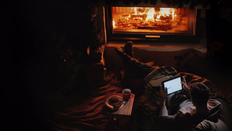 a man with a tablet in his hands has a good time at home by the fireplace