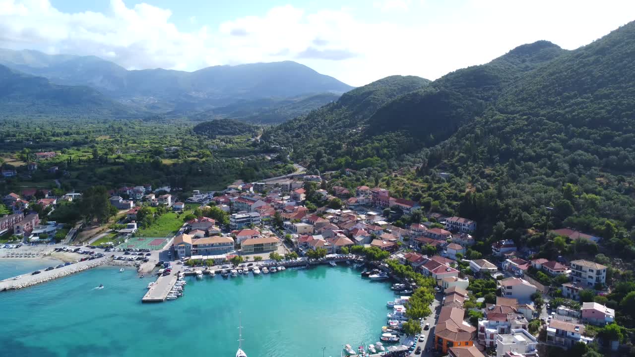 Vista aérea de cidade costeira com água turquesa e montanhas