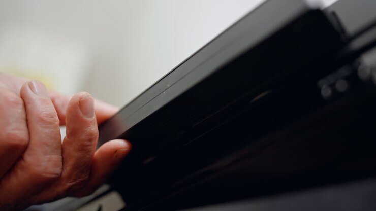 Přední panel Video Home System. Detailní záběr zblízka z nízkého úhlu. Páska vyjíždí ven a ruka ji odebírá
