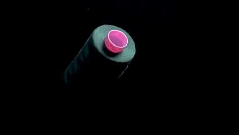 green thread on spool bobbin spin and unroll on black background slow mo