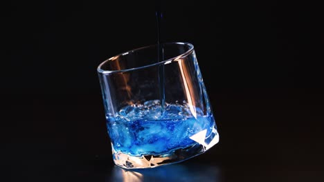 líquido azul vertido en un vaso con hielo