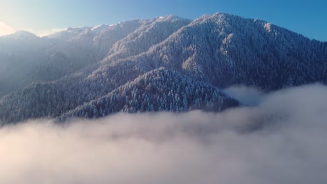 Enchanting-winter-drone:-Snow-capped-peak,-moving-clouds,-serene-beauty