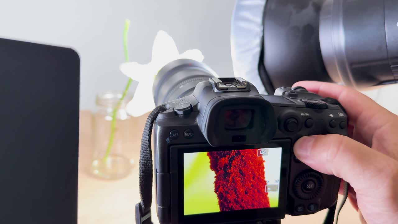 A camera captures detailed macro shots of a flower's anatomy in a well-lit studio environment