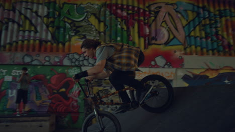 energetic boy training skills on bmx bike at skatepark. biker flipping outdoors.