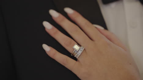 bride's hand with diamond wedding ring resting her hand on groom's chest, close up