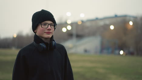 a coach holding a soccer ball in a field with a whistle in his mouth, playfully throws the ball at a young boy wearing glasses and a beanie in a stadium, then collects it back