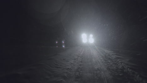 half-track driving in the night in jotunheimen in norway. the half-track has skies in front. its night and the snow are falling. filmed on a gimbal in 4k. this is a slow-motion clip.