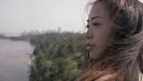 close up of attractive asian girl with long black hair, vancouver downtown in background, slowmo