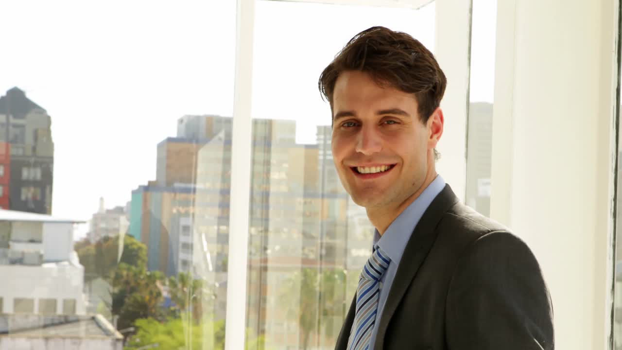 hombre de negocios mirando por su ventana y luego volviéndose a la cámara