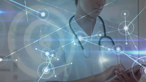 animation of connected dots and dartboard over caucasian female doctor using digital tablet