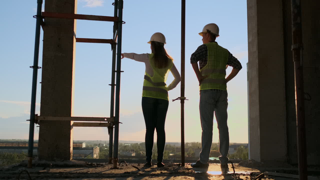 mujer arquitecta y hombre constructor en el sitio de construcción vista trasera. trabajo en equipo de desarrollo de edificios y concepto de personas. mujer arquitecto y hombres constructor en
