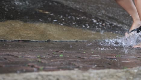 low angle shot of feet wear flipflop running on the heavy pouring rain day, flooded street, stormy typhoon monsoon seasons, wet feet rushing on the water puddle, soaking wet sandals on the raining day