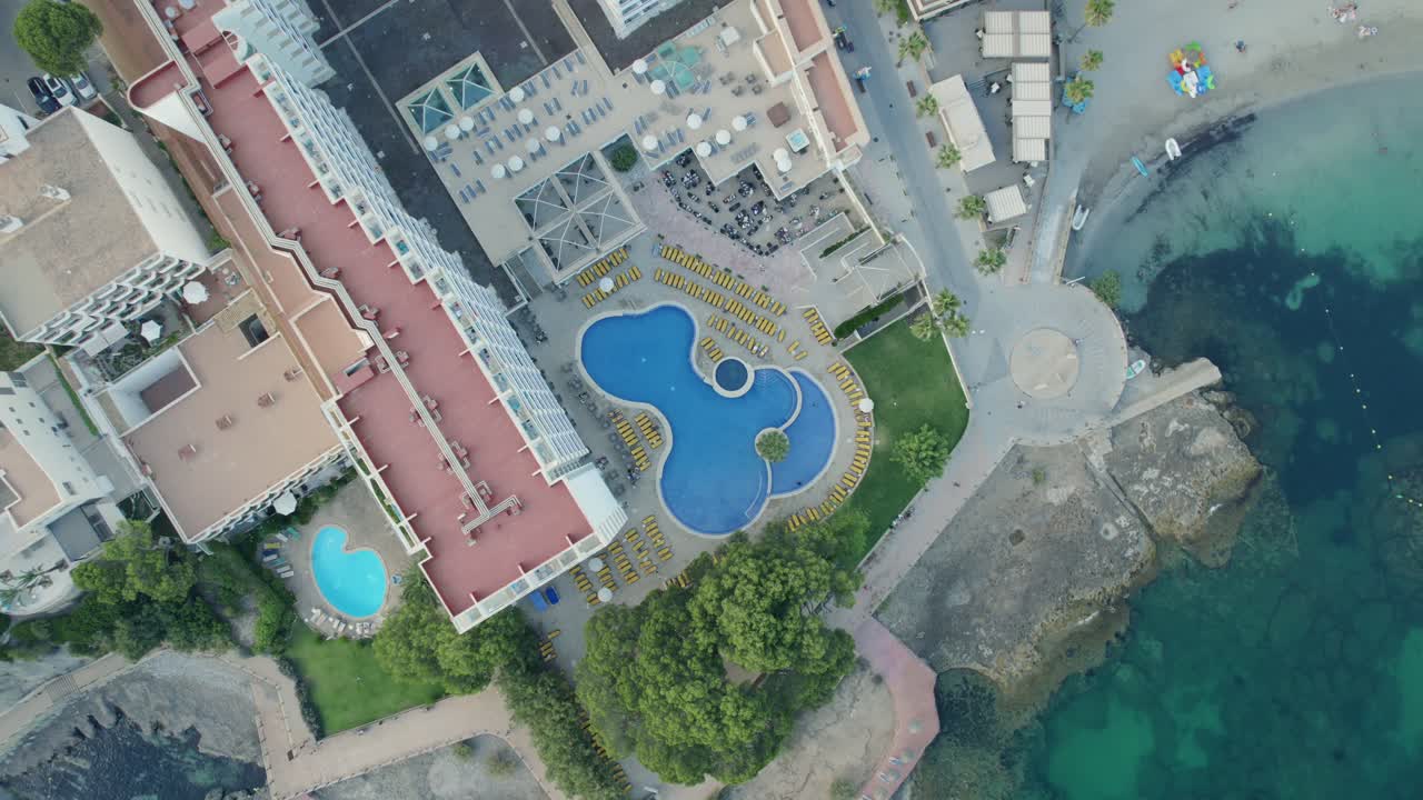 Top down lowering view of a large resort in Mallorca at the clear sea.