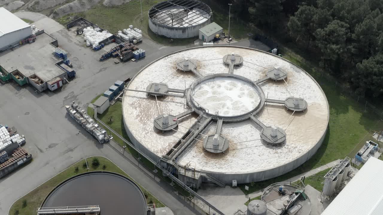 Aerial circling shot of large circular water treatment or settling tanks at industrial factory, Veille-Saint-Girons, France