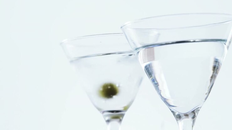 Olive che cadono in due bicchieri da cocktail