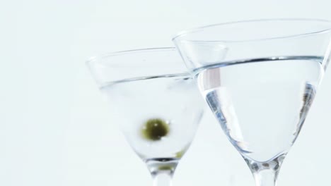 aceitunas cayendo en dos copas de cóctel