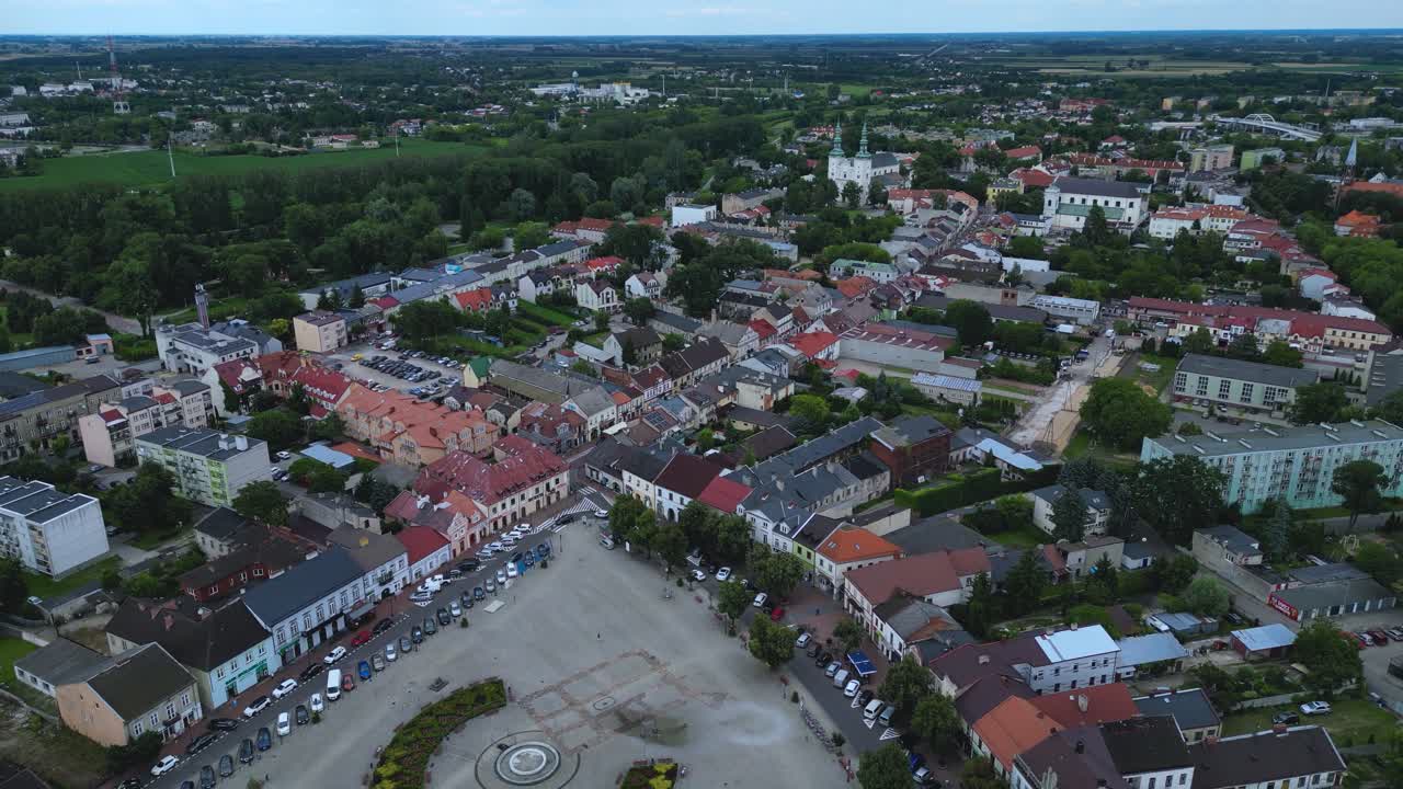 En omvendt dolly-bevegelse, som trekker seg tilbake fra den historiske hovedplassen (Rynek) i Łowicz, Polen. Avslører byens sentrum, historisk arkitektur og det omkringliggende grønne bybildet