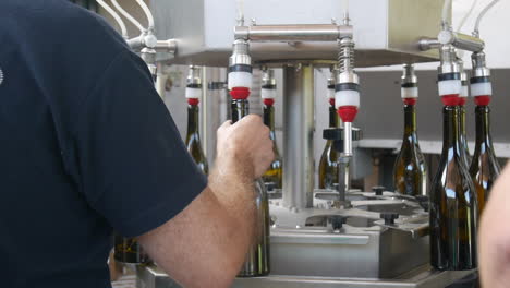 workers using a machine to bottle some wine