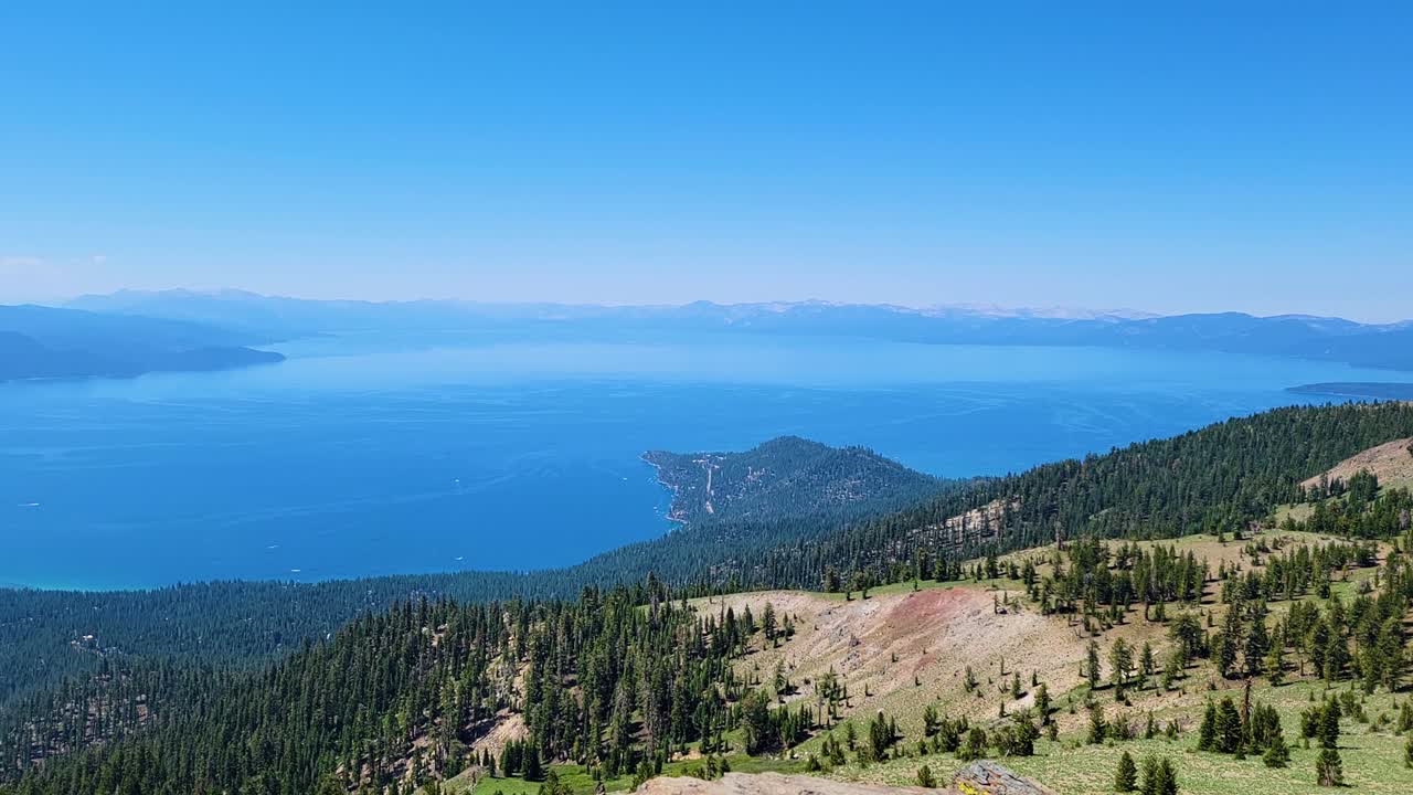 Acque cristalline e di un blu brillante del Lago Tahoe circondate da una pineta e viste sulle montagne durante un'escursione in California