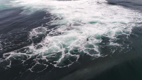large wave crashes over with whitewater explosion, top view aerial ocean motion
