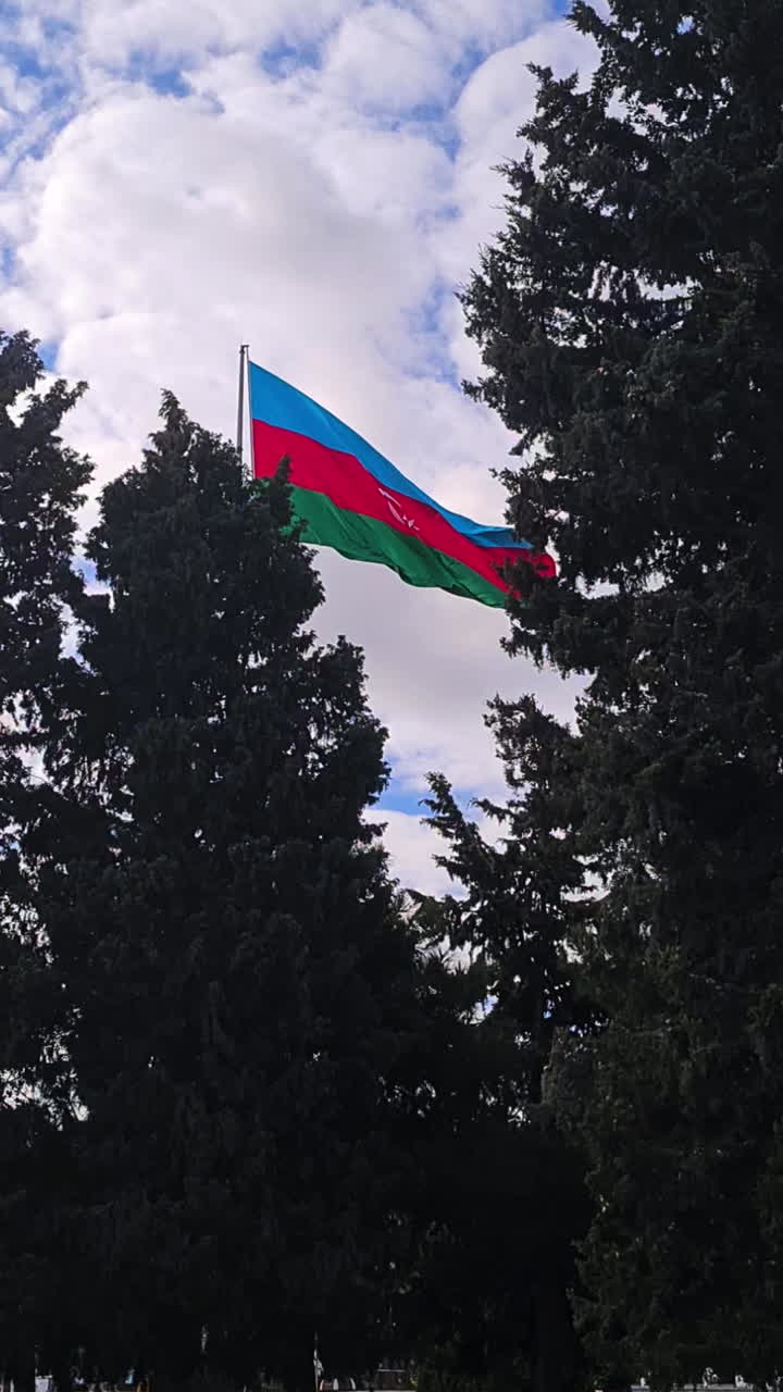 вертикальный вид азербайджанского национального флага, развевающегося на столбе в парке милли, баку
