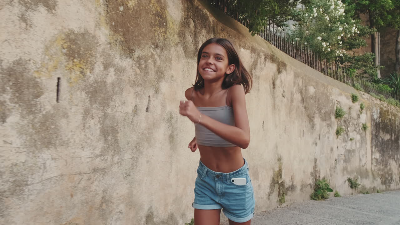 Ragazzina che corre e sorride felice su una strada di ciottoli
