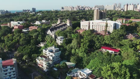 Aletheia-University-amid-large-vegetation-area-in-Tamsui-City,-New-Taipei-City-in-Taiwan,-Aerial