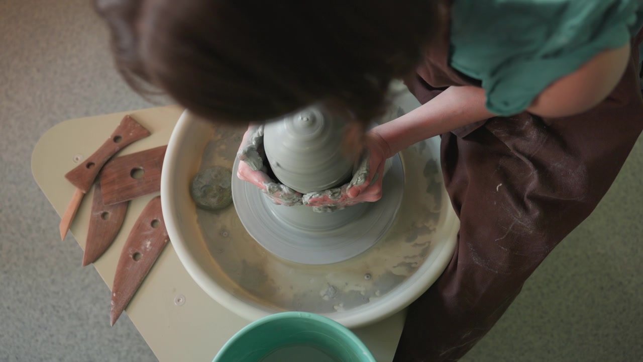 Una donna trasforma l'argilla in un vaso. Una vasaia modella e rifinisce meticolosamente il suo pezzo in ceramica. Un'attenta scultrice forma abilmente un'elegante ciotola da materiale argilloso malleabile.