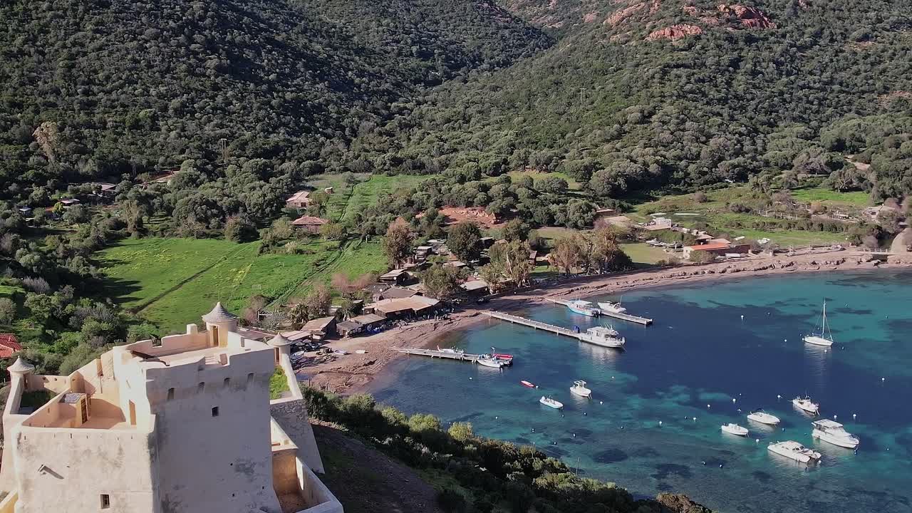 Vista de uma área costeira na Córsega com barcos e colinas verdes
