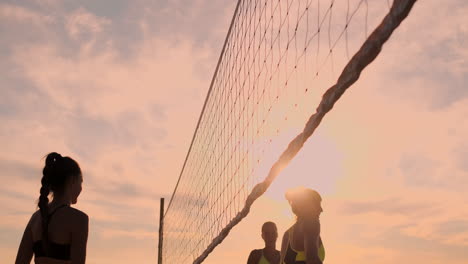 Grupo-De-Chicas-Jóvenes-Jugando-Voleibol-De-Playa-Durante-El-Atardecer-O-El-Amanecer-En-Cámara-Lenta.-Hermosas-Chicas-En-Bikini-Juegan-Voleibol-Profesionalmente-En-La-Arena