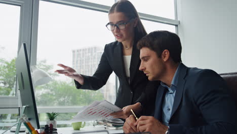 Office-managers-discussing-papers-looking-computer.-Workers-discussing-documents