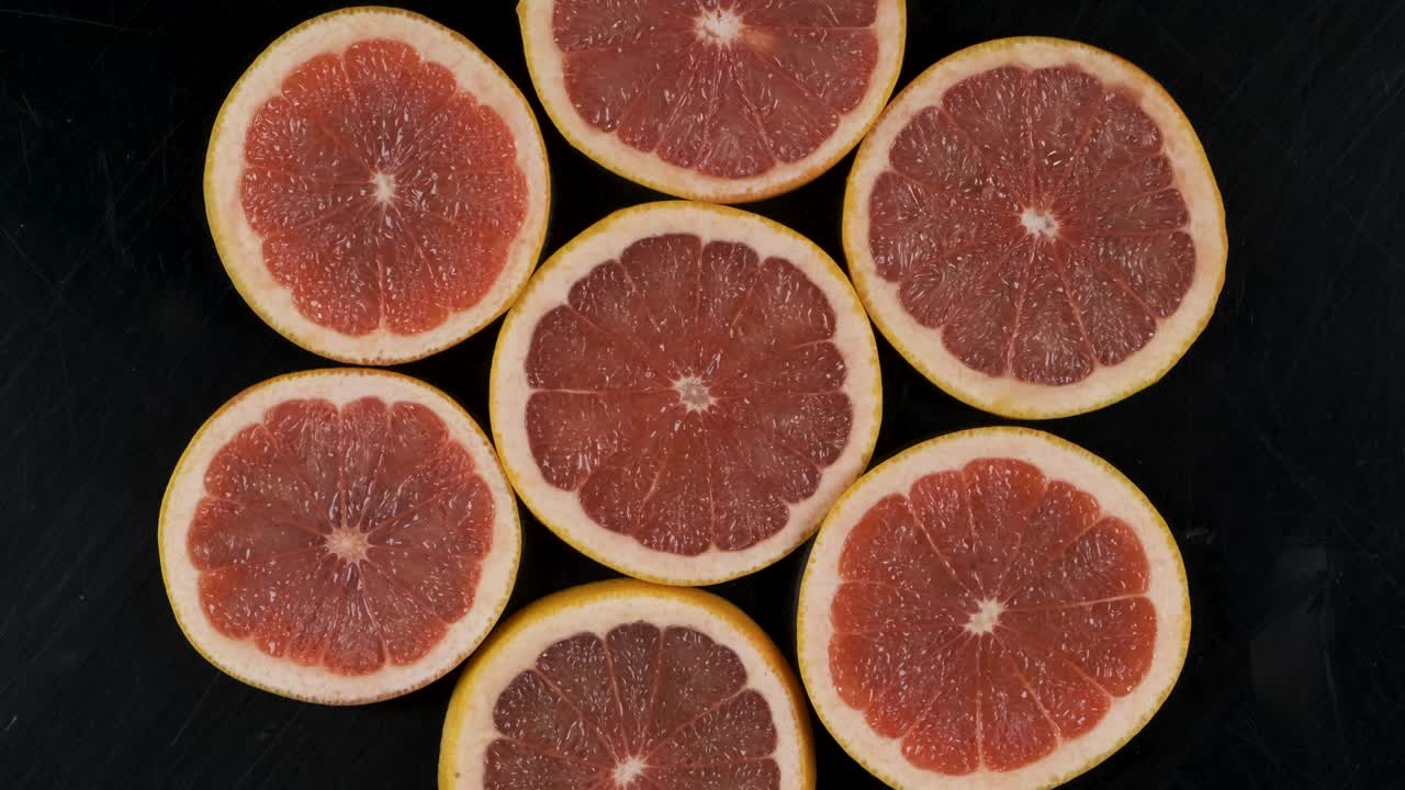 Collection of fresh grapefruit slices on black background. Rotation citrus fruit. Top view.