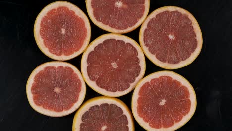 collection of fresh grapefruit slices on black background. rotation citrus fruit. top view.