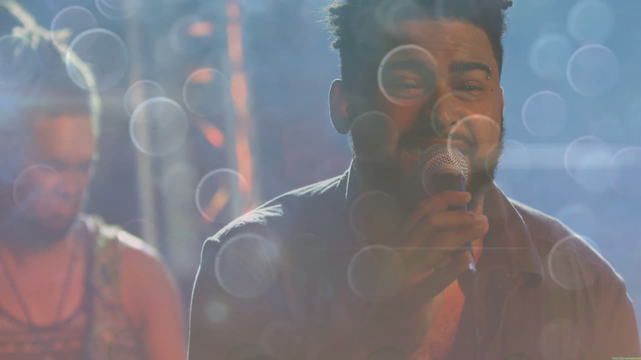 Singer and guitarist performing on music concert stage, with animated amber and blue light flares