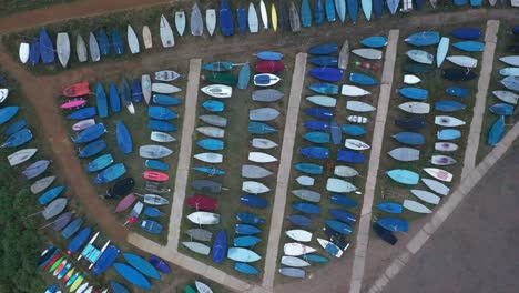 rising aerial footage revealing yachts, boats, kayaks and dinghys in a boat yard beside an estuary in norfolk, england