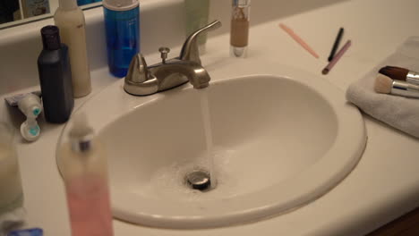 View-of-the-on-suite-bathroom-with-the-water-running-and-beauty-products-on-the-vanity---slow-pan