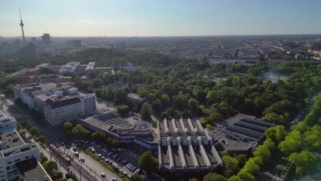 Sez and Volkspark Friedrichshain in Berlin, showcasing its lush greenery, a passing tram on a sunny day. Best aerial view flight fly reverse drone