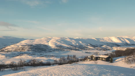 snowy mountain landscape and cabin by the hill in haugastol norway - wide shot