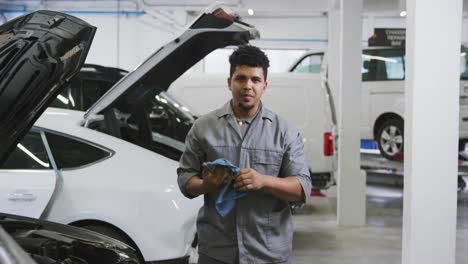 african american male car mechanic cleaning his hands with a rag and looking at the camera